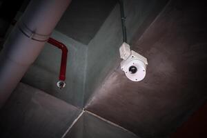 A security camera is mounted on the ceiling of a building photo