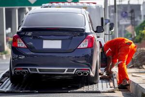 A man in an orange shirt is fixing a car on a tow truck photo