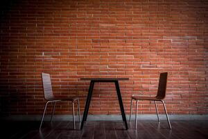 Two chairs and a table in front of a brick wall photo