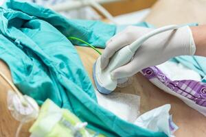 A person in a hospital gown is using an ultrasound machine photo