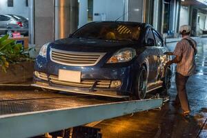 A man is loading a car onto a flatbed photo