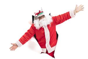 Santa Claus from a hole in paper.Christmas Holidays. Man in a New Year's suit from the wall photo