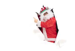 Santa Claus from a hole in paper. Man in a New Year's suit from the wall... photo