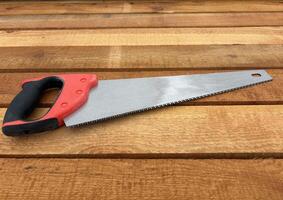 A wood saw lies on a stack of new lumber at a construction site or sawmill. photo