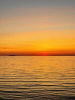 Calm sunset over the sea. The sky is painted with bright colors. Beautiful summer evening at the beach. Vertical photo. photo