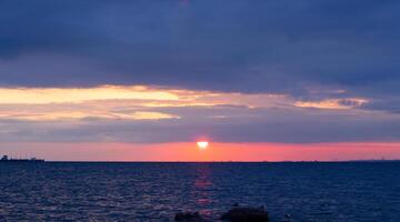 Scenic sunset over the sea. The sun is peeking out from behind the clouds. photo