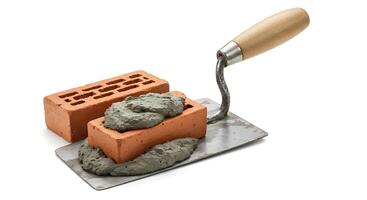 A brick and a trowel on a white surface photo
