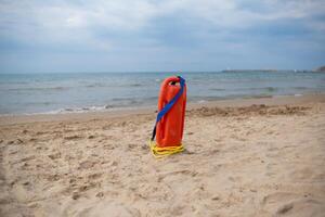 Lifeguard Buoy Stands on Sandy Beach Beside Calm Ocean Under Cloudy Sky During Early Evening photo