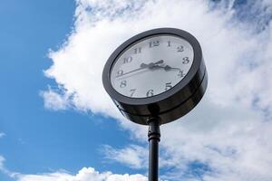 Vintage Clock Mounted on a Pole Against a Bright Blue Sky During the Day photo