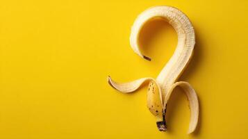 Curled Banana Peel Forms a Question Mark Shape on Vibrant Yellow Backdrop, Evoking Humor and Curiosity in a Whimsical Fruit Composition photo