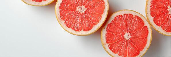 Grapefruit Halves Arranged Diagonally on a Clean White Surface Showcasing Vibrant Pink Flesh and Rind Textures photo