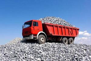 A red dump truck is sitting on top of a pile of gravel photo