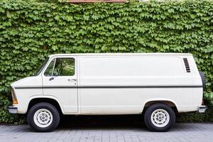 An old white van parked in front of a wall photo