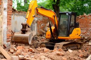 A construction machine is digging up a brick wall photo