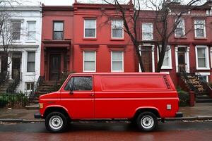 A red van parked in front of a row of red brick houses photo