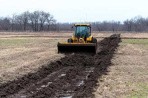 A tractor is plowing a field of dirt photo
