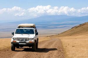 A jeep driving down a dirt road with mountains in the background photo