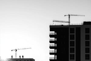 A black and white photo of construction cranes on a building