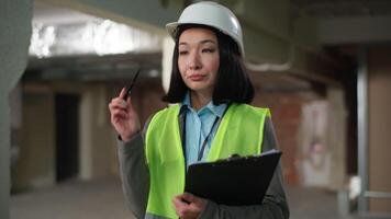 Thoughtful pensive Asian Korean Japanese woman thinking Chinese female write checklist notes document builder expert displeased inspector girl construction build plan architect technician contractor video