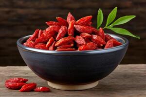 Bowl overflowing with dried goji berries and leaves on wooden table photo