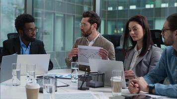 Caucasian leader analysis data graph report talking speaker statistics paper document multiracial colleagues business team diverse businesswomen businessmen meeting strategy plan presentation office video