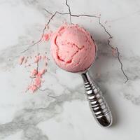 Pink ice cream scoop on marble with scattered crumbs. photo