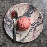 Strawberry Ice Cream Scoop on a Marble Plate with a Spoon. photo
