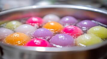 Colorful Tang Yuan Balls Simmering in Hot Water for Sweet Soup. photo