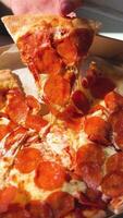 Pepperoni pizza, stretching cheese. Man takes slice of pizza. vertical footage close up video
