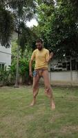 Man jumping and moving playfully outdoors in a tropical garden video