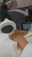 Esthetician uses method of photoepilation to remove hair follicles from the hands of the female client in the beauty salon. Vertical. video