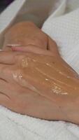 Before starting cosmetic treatment, special gel is carefully applied to client's hands using spatula by beauty salon professional. Close up. video
