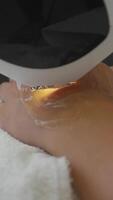 A cosmetologist uses the drug photoepilation to remove hair follicles from a female client's hands in a beauty salon. Vertical. video