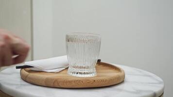 Service staff will place a glass of fresh, cold water on a tray for the client on the coffee table in the spa. Close up. video