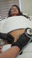 Cosmetologist conducts an ultrasonic anti-cellulite massage using a device designed to shape the body, focusing on the abdominal area. video