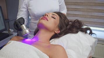 Beauty therapist employs cutting-edge LED light therapy apparatus to revitalize client's neck, rejuvenating skin and bringing it back to its optimal state. video