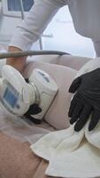 In clinic, cosmetologist uses vacuum roller device with manipulator to perform anti-cellulite massage of client's thighs. lymphatic drainage stimulation and metabolic processes acceleration. video