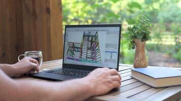 3D architectural modeling on laptop in outdoor workspace, User designs wooden structure using CAD software on laptop surrounded by nature and tea video