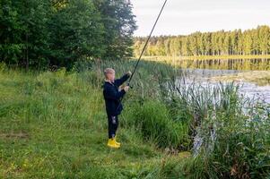 A young boy is fishing on a lake photo