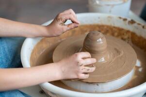 A child is making a pot on a potter's wheel photo