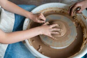 A woman is making a pot on a potter's wheel photo
