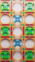 Colorful interlocking plastic gears and shapes in a vertical pattern. Abstract toy construction background. Bright, playful, and mechanical design. Ideal for education or creativity themes. video