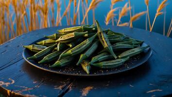 Pile of Fresh Okra Pods on Plate Next to Water photo