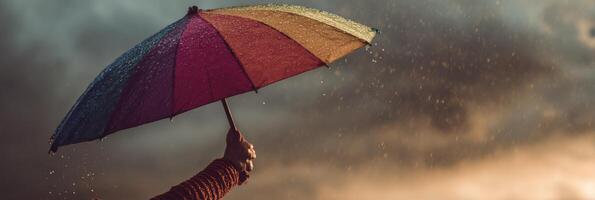Hand Holds a Rainbow Umbrella During a Storm, Symbolizing Support and Resilience Under Challenging Weather Conditions photo