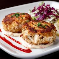 A plate of crab cakes and salad on a table photo