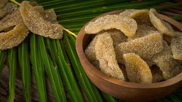 Sweet Candied Ginger Slices in a Wooden Bowl with Palm Leaves. photo