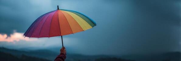 Holding a Rainbow Umbrella Against Stormy Skies, a Symbol of Hope and Support in Challenging Times photo