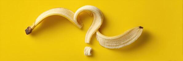 Curled Banana Peel Forming a Whimsical Question Mark on a Bright Yellow Background photo