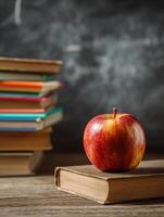 Bright Red Apple Resting on Stacked Books With Chalkboard Background in a Classroom Setting During the Day photo