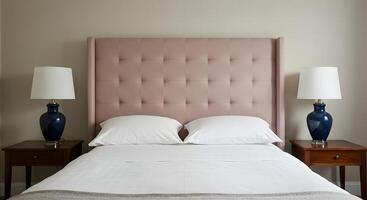 Elegant bedroom with a plush pink tufted headboard and matching bedside tables with dark blue lamps photo